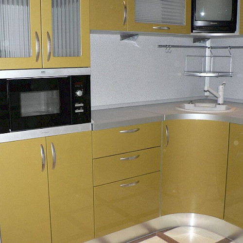 Нижняя часть угловой кухни с жёлтыми фасадами